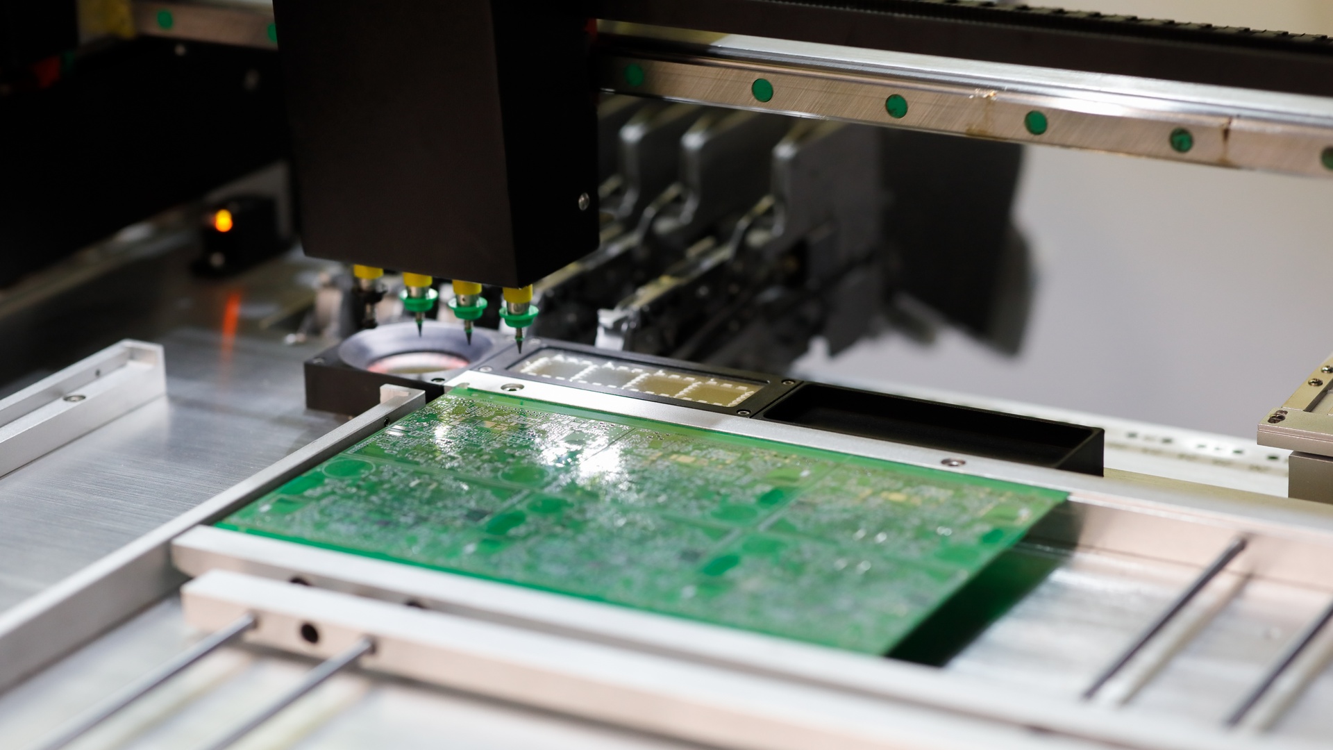 A close-up of a small gantry system with a metal base. Multiple needles attached to the moving head work on a chip.