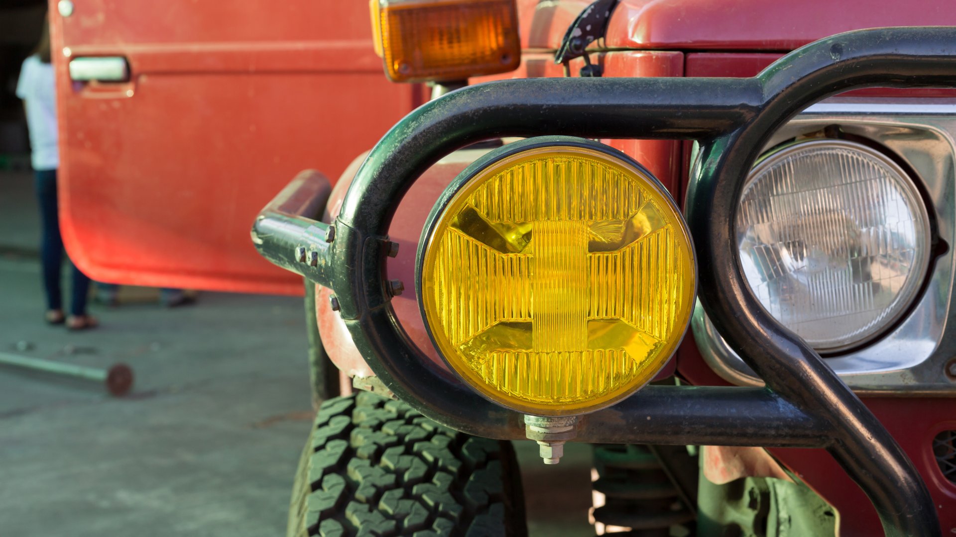 A close-up of the right-most pair of headlights on an off-road vehicle. One is yellow and the other is white.