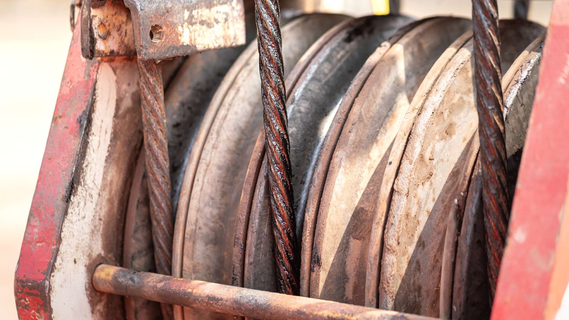 Three crawler drums are attached to a lifting crane with three wire slings. The wire slings are well used.