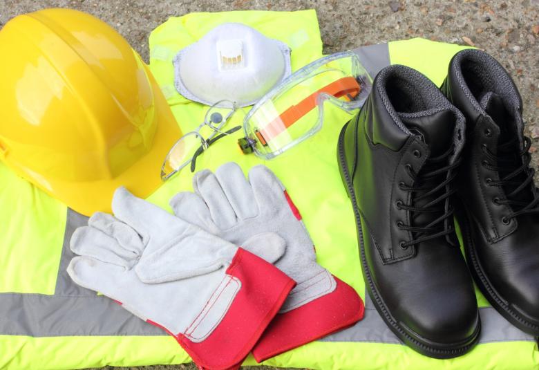 Several pieces of personal protection equipment lie on a concrete surface, including a helmet and gloves.