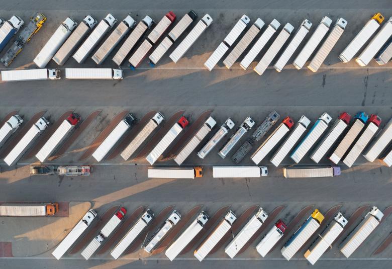 A bird’s eye view of a large parking lot filled with several semi-trucks all parked in diagonal parking spots.
