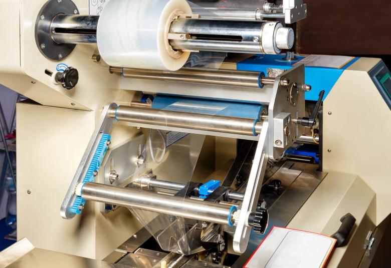 A production line with an industrial bubble wrap machine. The machine is currently off and there's tape in the top roll.