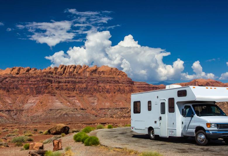 A white recreational vehicle parked on the side of the road in a desert canyon in a southwestern American state.